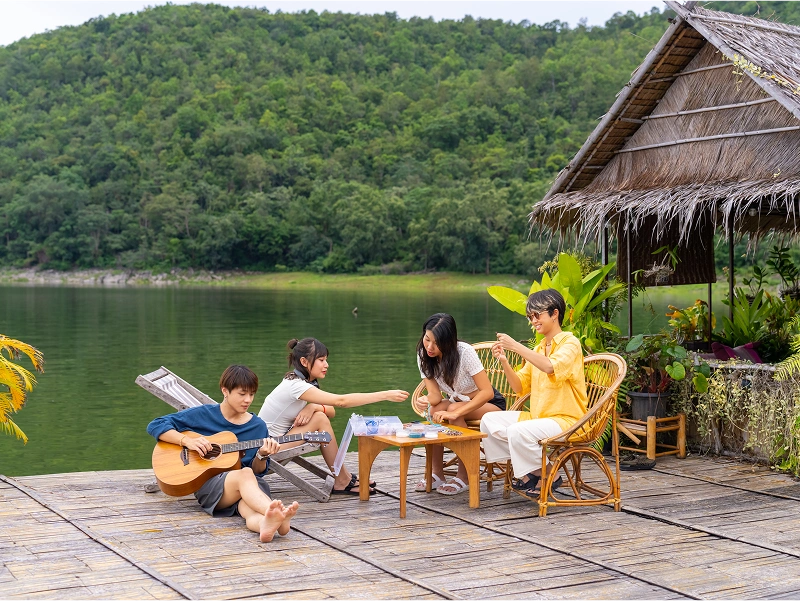 Family relaxing by lakeside with guitar.