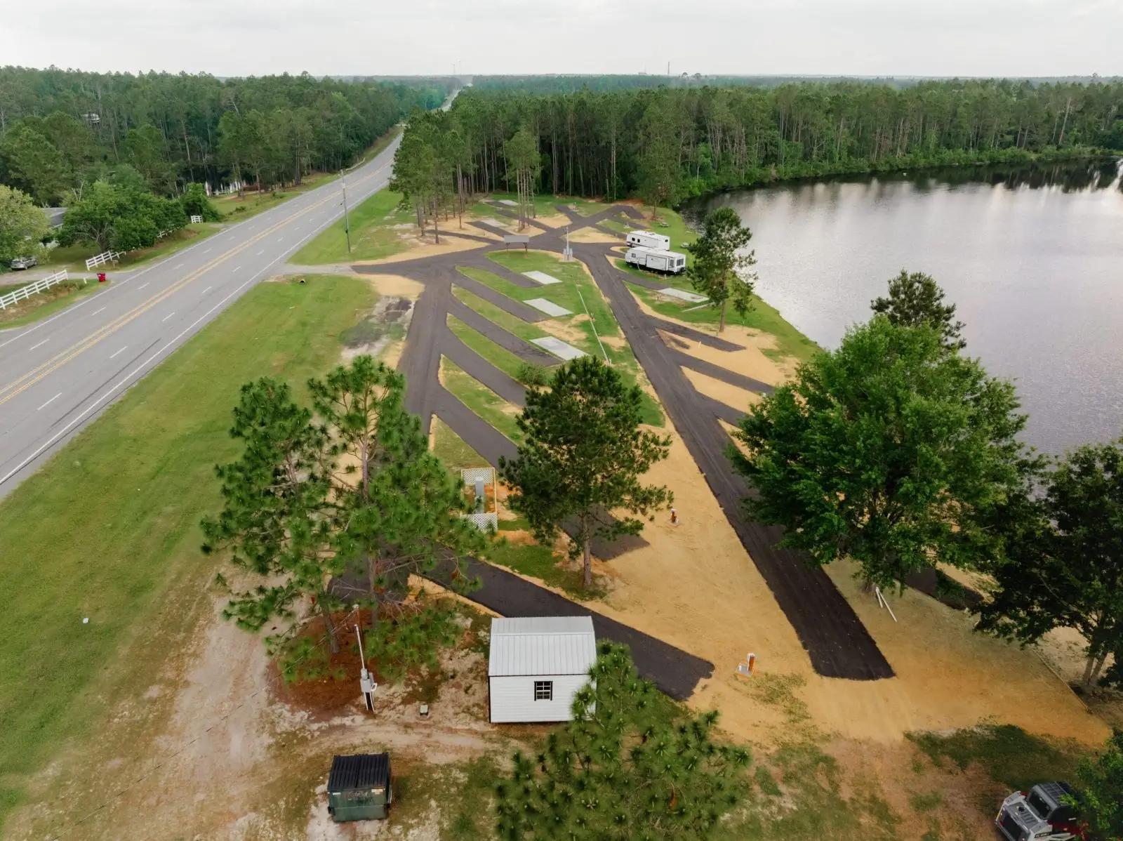 Aerial view of a landscaped park with pathways, trees, and a nearby lake.