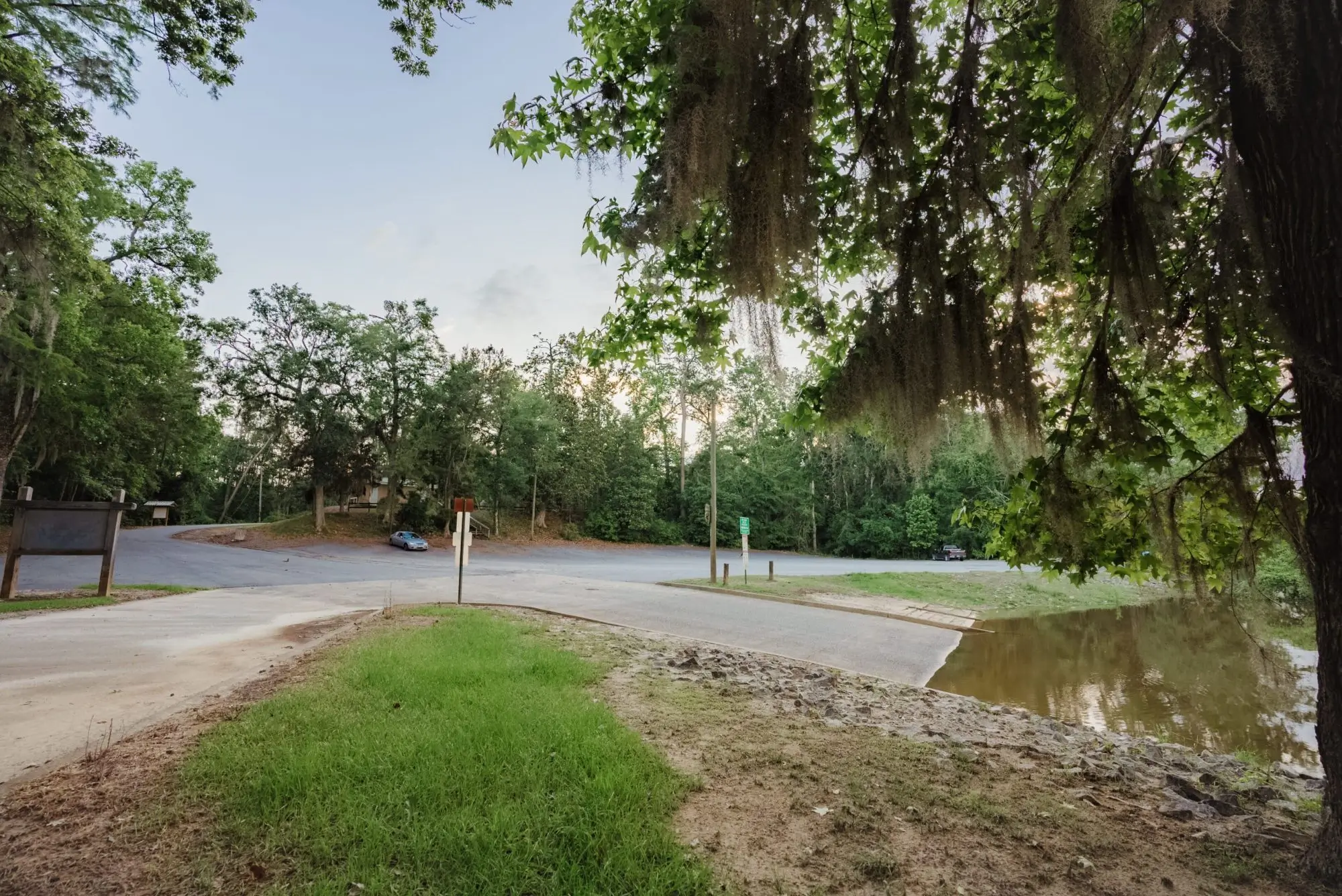 A quiet street corner with trees and grass under a clear sky.